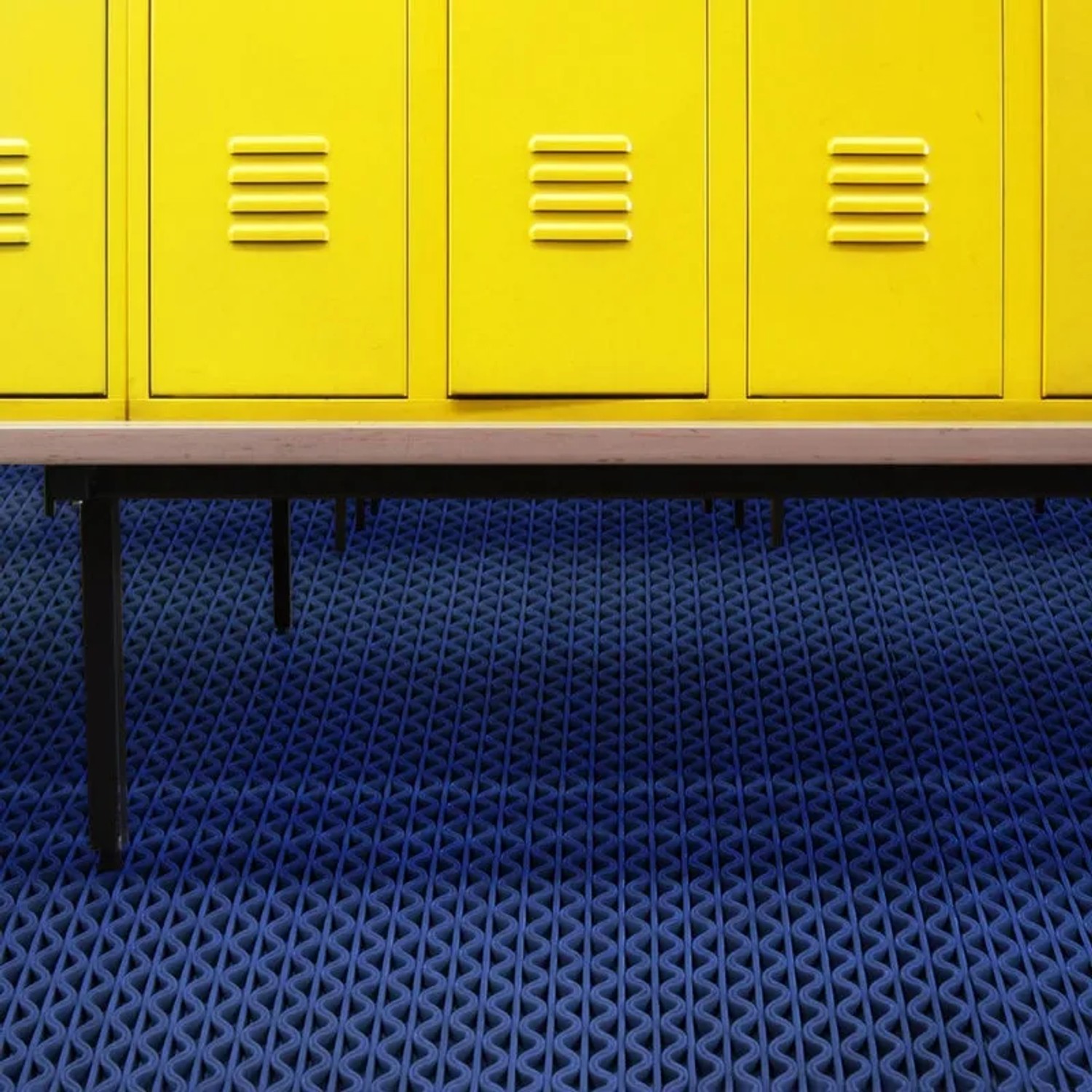 Blaue KARAT Hygienematte 90x900 cm für Barfußzonen vor gelben Spinden.
