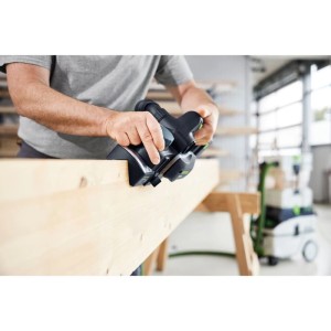 Mann fasst mit Festool Akku-Handhobel und Fasensohle einen Holzbalken. Präzises Fasen von Kantholz.