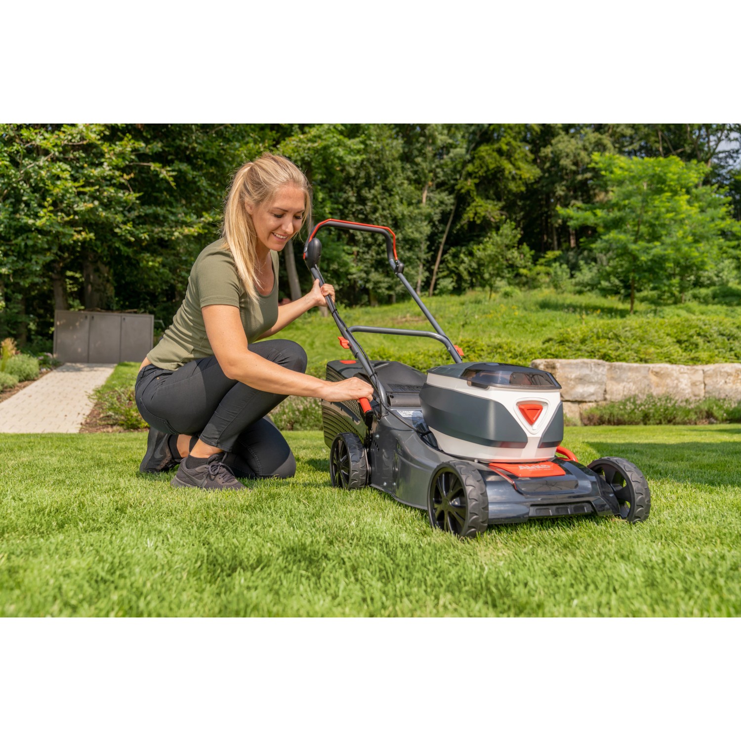 Frau bedient Al-Ko Akku-Rasenmäher 42.2 Li Comfort auf Rasenfläche.