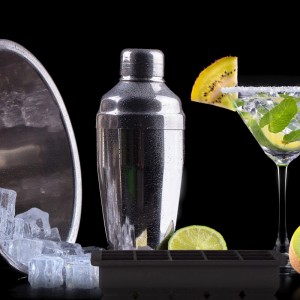 Schwarze Silikon Eiswürfelform für 15 Würfel, daneben Cocktailshaker, Eiswürfel und ein Cocktailglas mit Limette und Minze.
