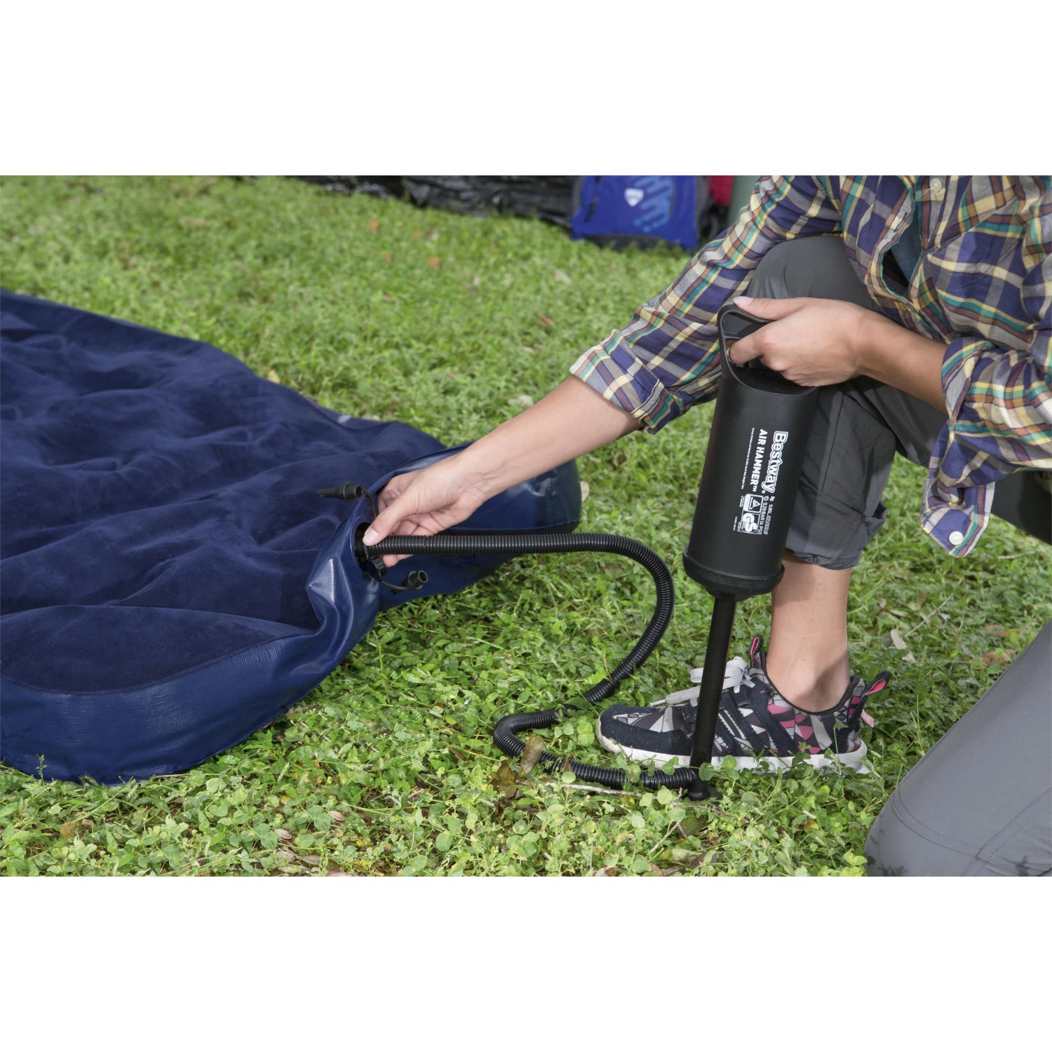 Aufpumpen eines blauen Single-Luftbetts 185x76x22 cm mit einer Luftpumpe im Camping-Einsatz.