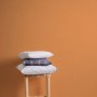 Orangefarbene Vliestapete Uni im Kinderzimmer mit Kissen auf Hocker.