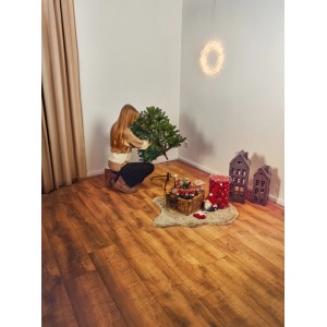 Frau setzt künstlichen Weihnachtsbaum Hartola (150 cm) zusammen. Dekoration im Raum.