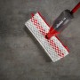 Vileda Sprüh-Wischer 1-2-SprayMax auf grauem Boden, Reinigungsgerät mit rotem Griff und weiß-rotem Bezug.