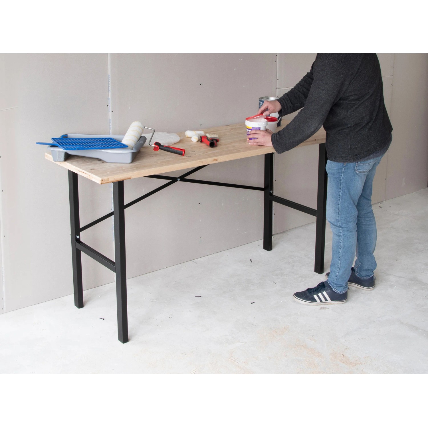 rikta Werkbank (159x85x58cm) mit Holzplatte und schwarzem Stahlgestell, genutzt von einer Person.