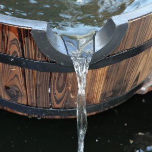 Detailaufnahme des Holzfass Brunnen Mosel mit fließendem Wasser.