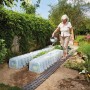 Frau gießt Pflanzen unter Garantia Pflanztunnel Sunny 5er-Set im Garten.