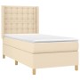 Cremefarbenes Boxspringbett 90x200 cm mit Matratze und gestepptem Kopfteil.