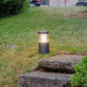 Moderne schwarze LED Sockelleuchte Lucius aus Aluminium im Garten. Spritzwassergeschützt, warmweißes Licht für Wege.