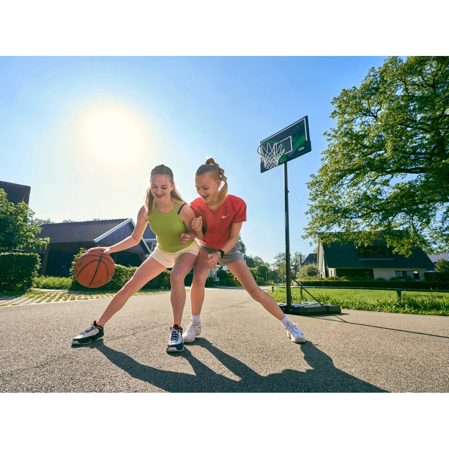 Zwei Mädchen spielen mit dem Salta Basketballständer Forward (108x362cm) im Freien.