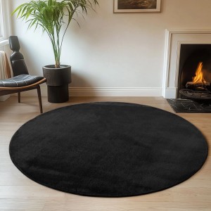 Runder, schwarzer Kurzflorteppich Ayyildiz Joy (Ø 80 cm) im Wohnzimmer.