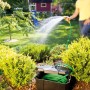 Heissner Garden Power Box im Garten mit Schlauch und Person beim Gießen. Stromverteiler für Teichpumpen.