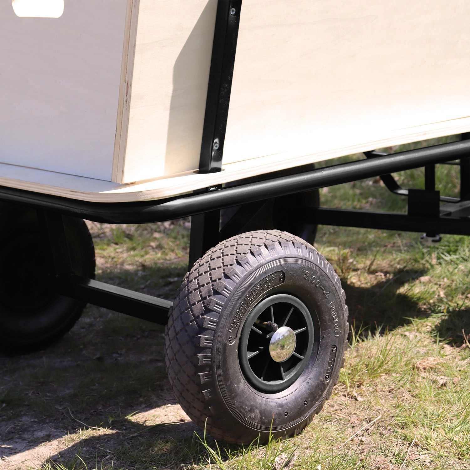 Detailaufnahme: Schwarzer Sunny Bollerwagen Billy Beach Wagon mit Holzaufbau und robusten Reifen.