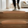 Beige, selbstklebende Treppenmatten auf Holzstufen. Eine Person nutzt die rutschhemmenden Stufenmatten für Komfort & Sicherheit.