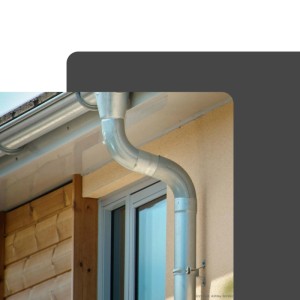 Silberner Zambelli Fallrohrbogen 40 Grad aus verzinktem Stahl, an Hauswand mit Dachrinne.