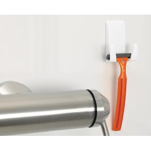 Weißer Tesa Rasiererhalter mit orangefarbenem Rasierer an Badezimmerwand.
