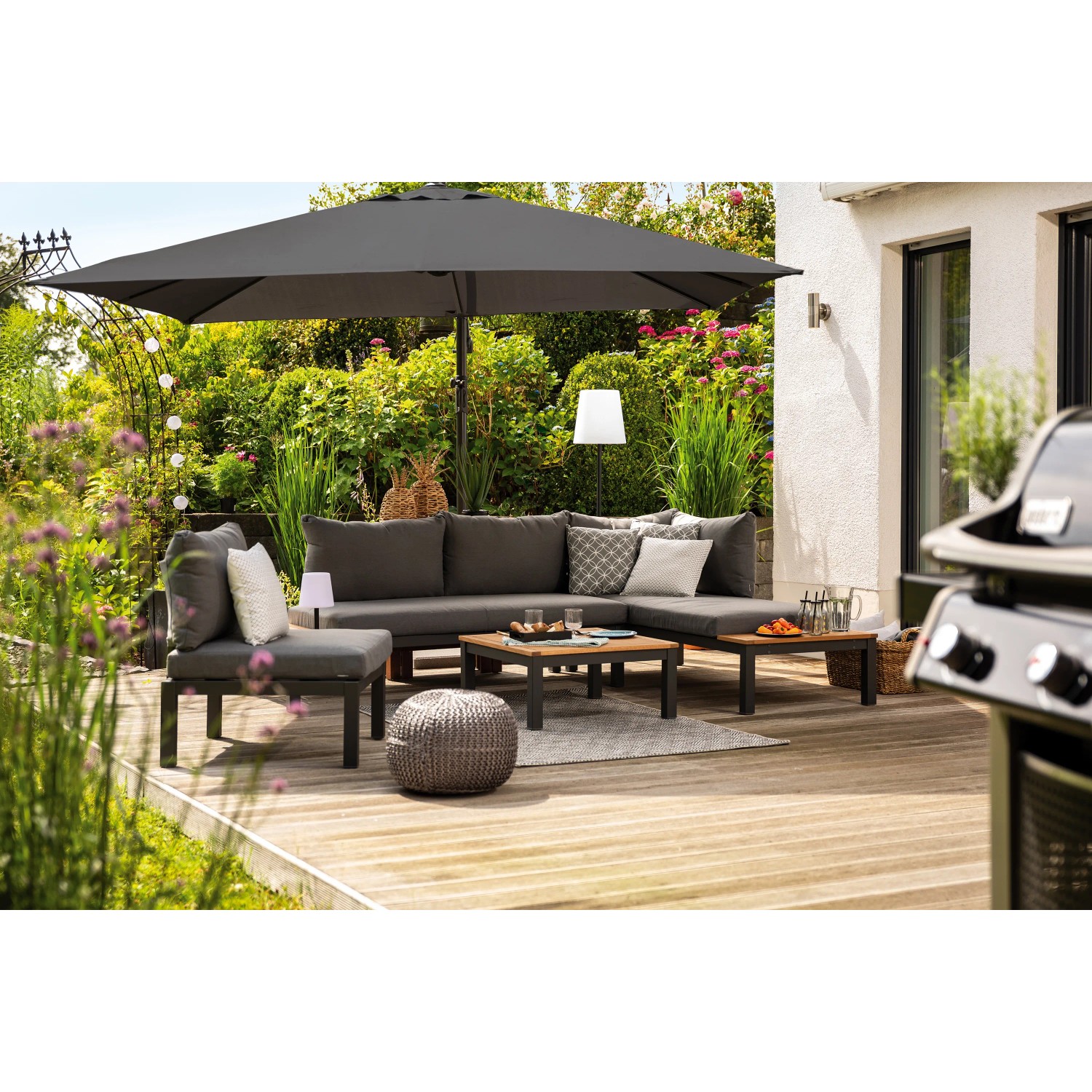 Grauer Lounge-Sessel Bonlee aus Aluminium mit Auflagen und Kissen als Teil einer Gartenmöbel-Gruppe.