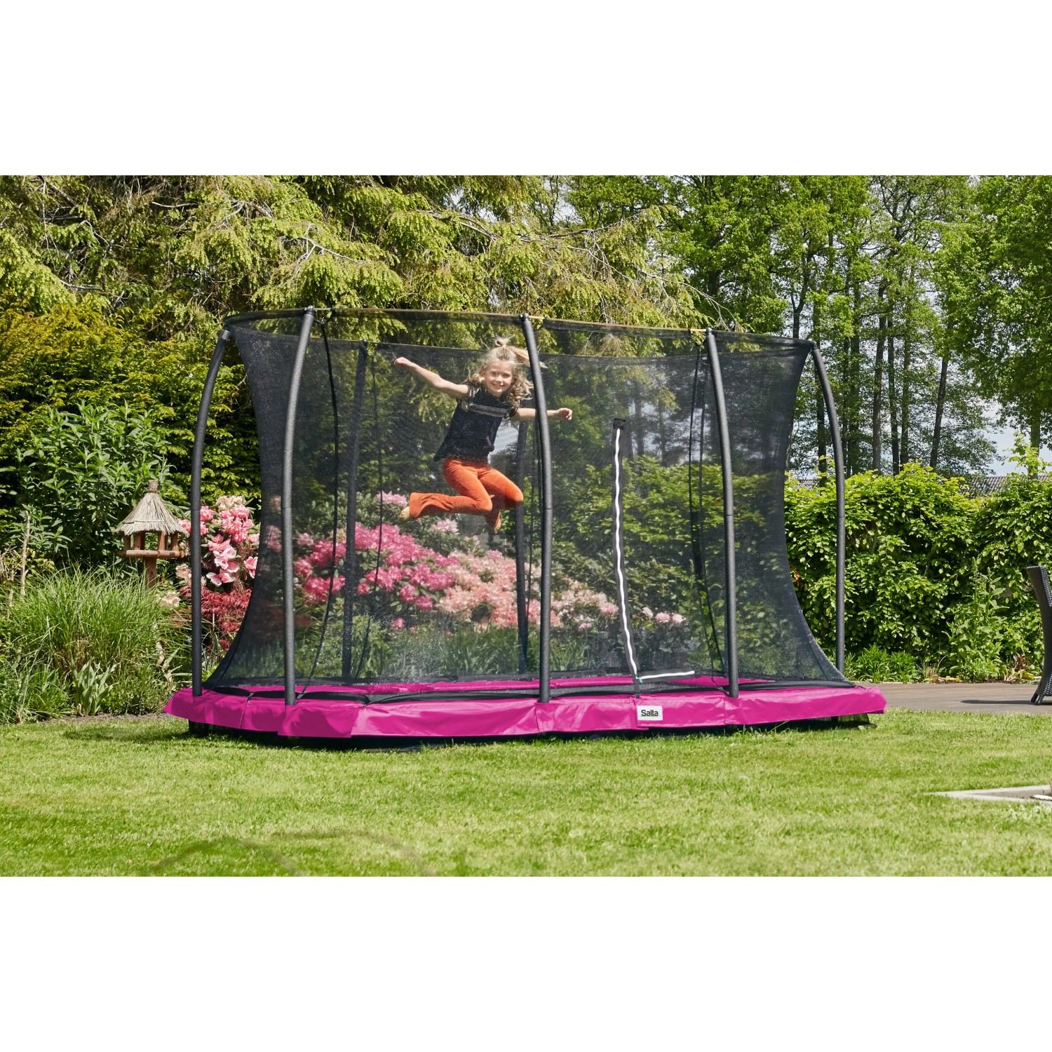 Mädchen springt auf pinkfarbenem Salta Bodentrampolin Comfort Edition mit Sicherheitsnetz im Garten.