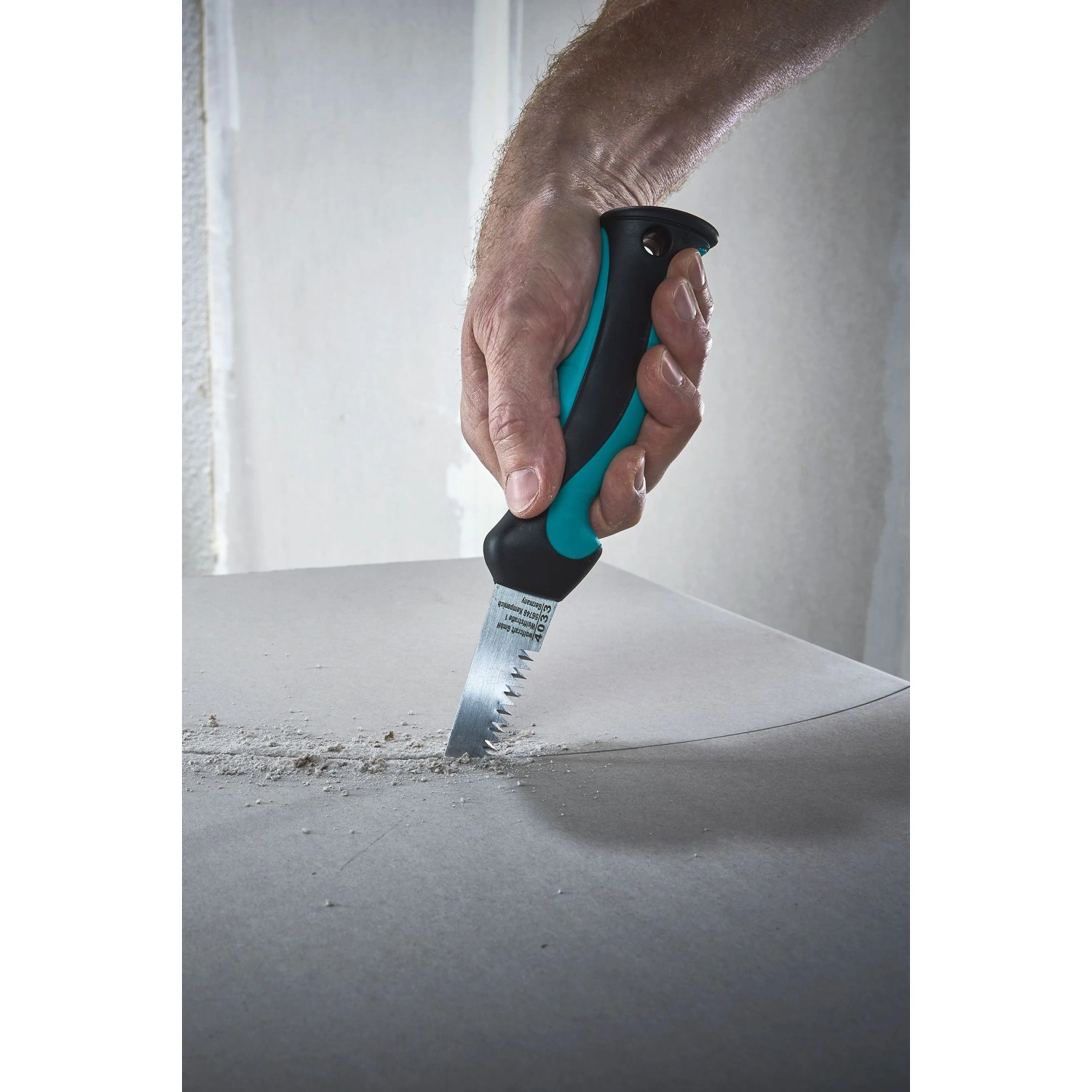 Hand sägt mit wolfcraft Handstichsäge mit 2-K-Griff präzise in Gipskartonplatte. Ideal für Trockenbau.