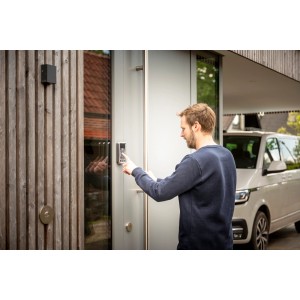 Mann bedient silberne Abus Bluetooth-Tastatur Hometec Pro CFT3100 an Haustür.