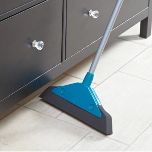 Leifheit Schaumstoffbesen Soft & Easy mit blauem Kopf und grauem Schaumstoff unter einem Schrank.