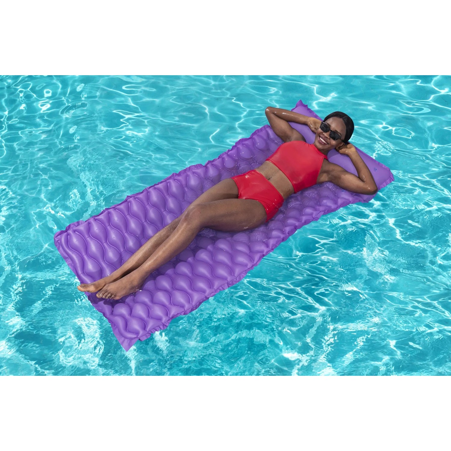 Frau entspannt auf lila Bestway Luftmatratze Float'n Roll (213x86cm) im Pool.