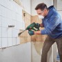 Mann entfernt Fliesen mit Bosch Akku-Bohrhammer UniversalHammer 18V. Bohrhämmer für Heimwerker.