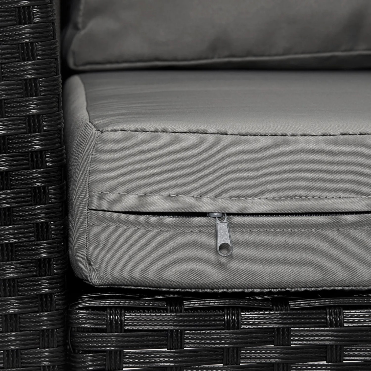 Detailaufnahme: Schwarze Polyrattan Gartenmöbel Sitzgruppe mit grauem Kissen und Reißverschluss.