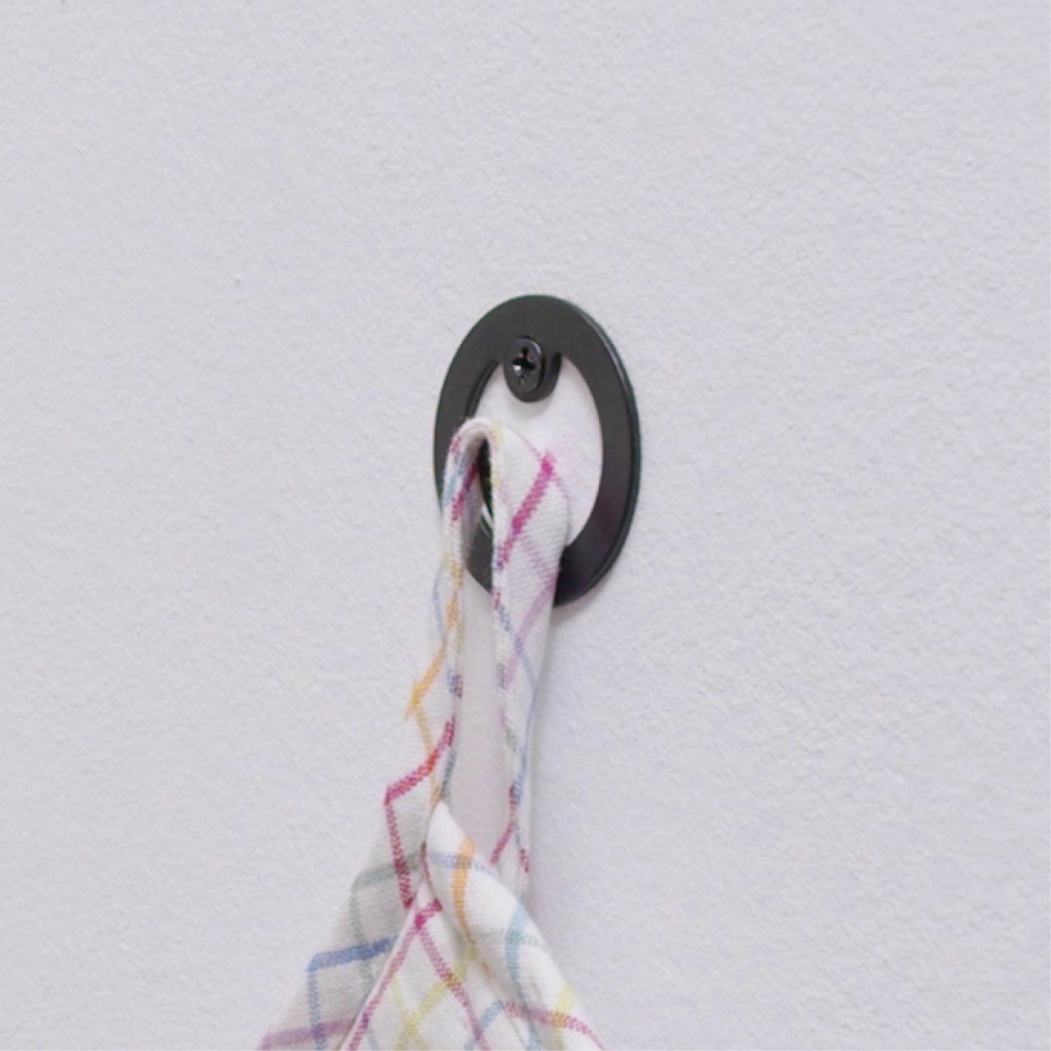Schwarzer, matter Wagner Wandhaken Hooks4home Retro mit Handtuch an weißer Wand.