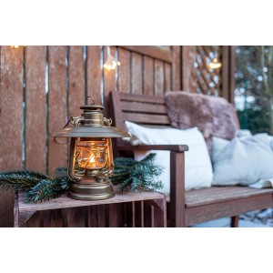 Feuerhand Sturmlaterne Baby Special Bronze mit Reflektorschirm auf Holzkiste vor Bank.