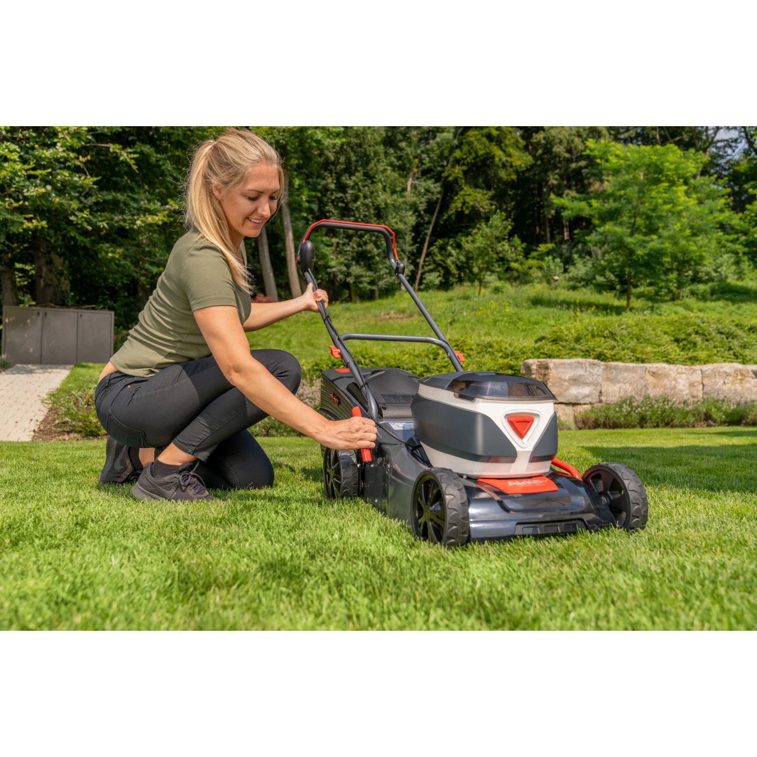 Frau bedient Al-Ko Akku-Rasenmäher 42.2 Li Comfort auf Rasenfläche.