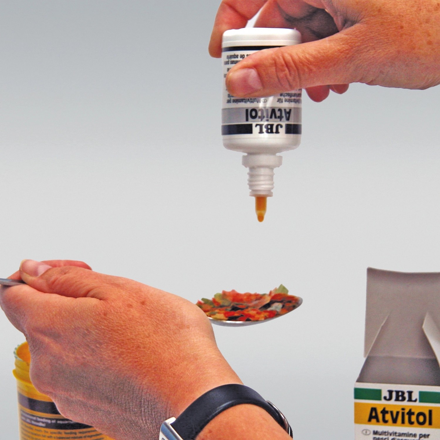 Dosierung von JBL Atvitol Multivitamin für Zierfische auf Futter im Löffel.