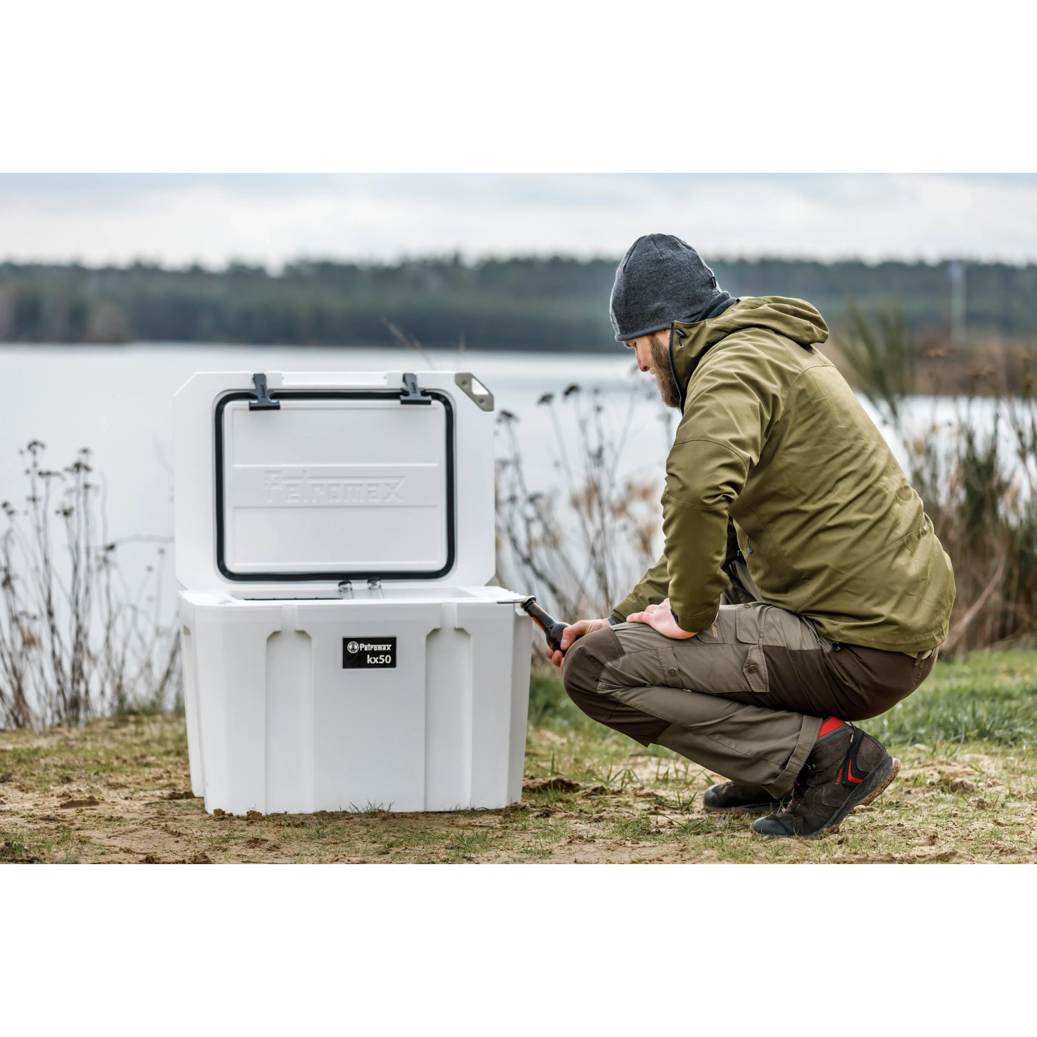 Geöffnete, sandfarbene Petromax Kühlbox 50L neben Person in Outdoor-Szene. Ideal für Camping.
