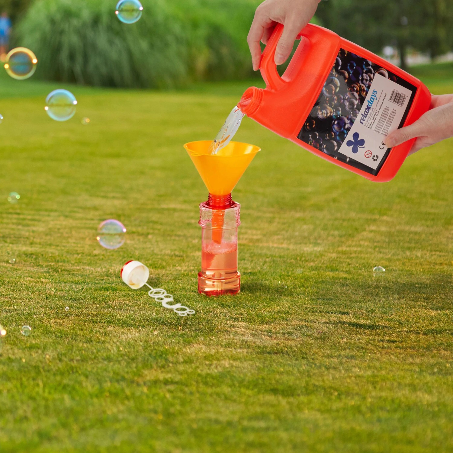 Orange Relaxdays Seifenblasen Nachfüllkanister (2L) wird mit Trichter in Flasche gefüllt. Seifenblasenflüssigkeit für Spiel & Spaß im Garten.