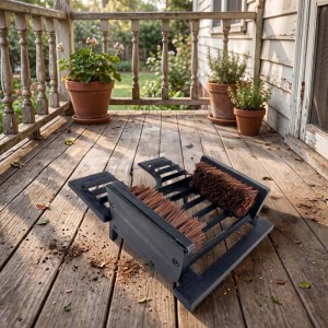 Schwarzer Gusseisen Schuhabstreifer mit braunen Bürsten und Schuhauszieher auf Holzterrasse.