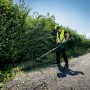 Mann arbeitet mit Metabo Freischneider-Aufsatz MA-FS 40 am Wegesrand.