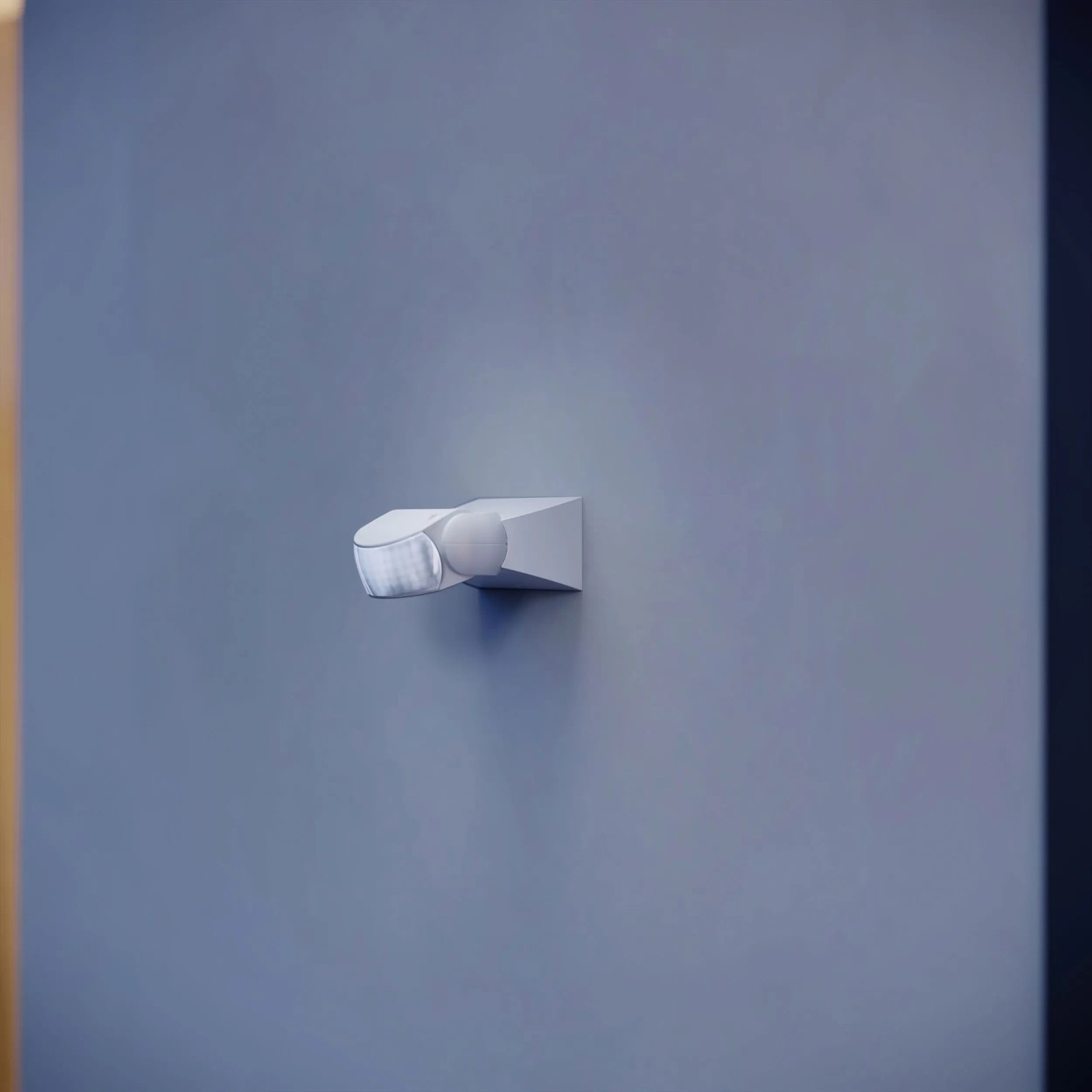 Weißer Steinel Bewegungsmelder IS 1 an grauer Wand. Sensor für Lichtsteuerung.