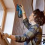 Frau schleift Holz mit Bosch Professional Akku-Exzenterschleifer GEX 12V-125. Schleifmaschine mit Staubbeutel.