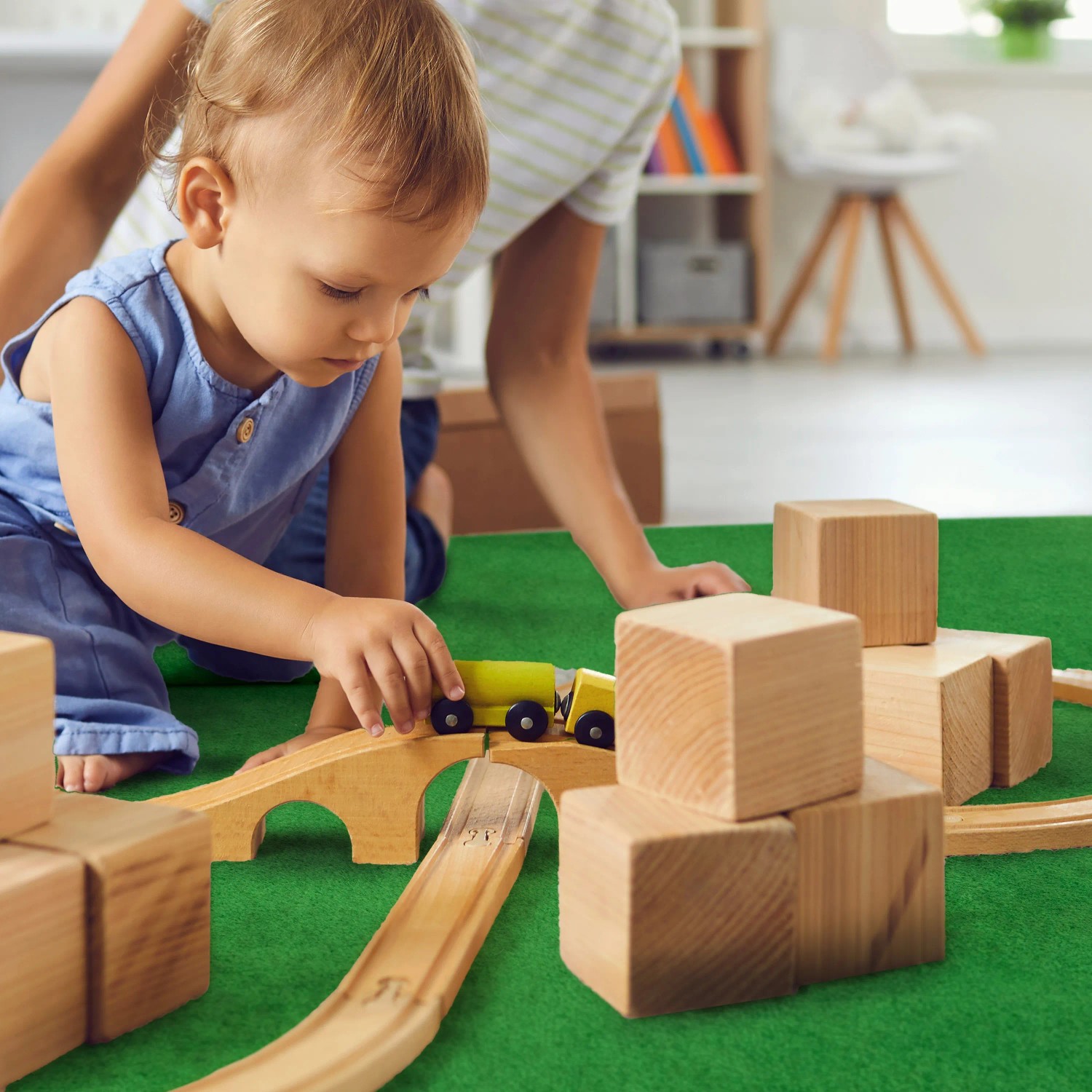 Kind spielt auf hellgrünem Primaflor Rasenteppich Garden B1 mit Holzspielzeug.