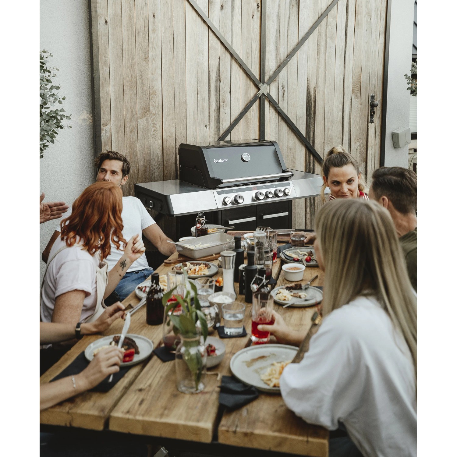 Enders Gasgrill Uniq Pro 3 beim Grillen mit Freunden. Schwarzer Grill mit Edelstahl-Elementen.