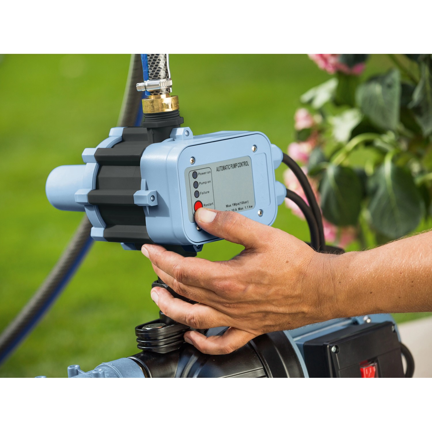 Hauswasserautomat HWA 3500: Pumpe mit Hand am Startknopf für die Gartenbewässerung.