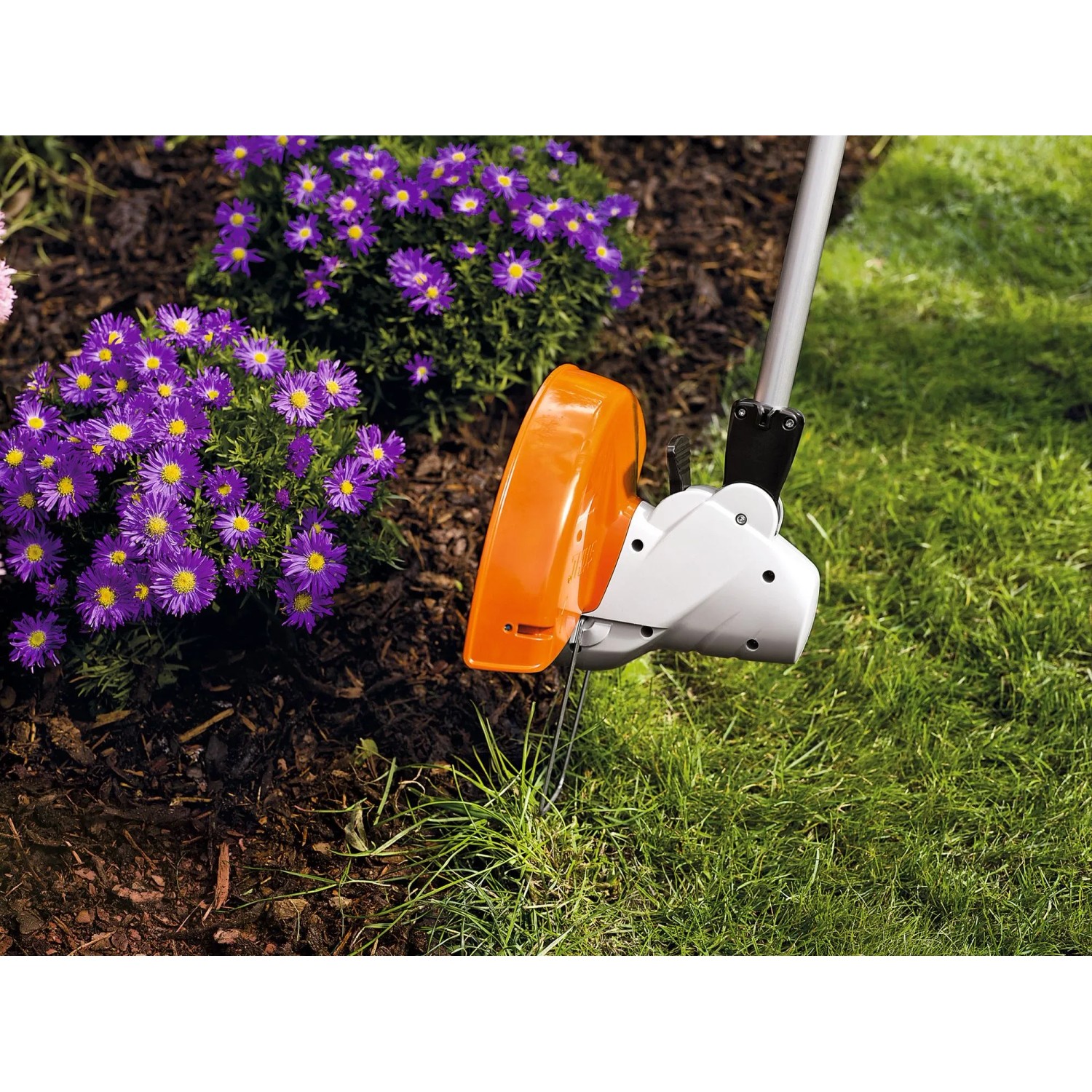 Stihl Elektro-Motorsense FSE 52 trimmt Gras im Garten. Orange-weißer Mähkopf mit Abstandshalter schützt Pflanzen.