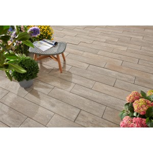 Verlegte Kann Außenplatten Rayon Sienna-Nuanciert 80x20x7,5 cm auf Terrasse mit Tisch und Pflanzen.