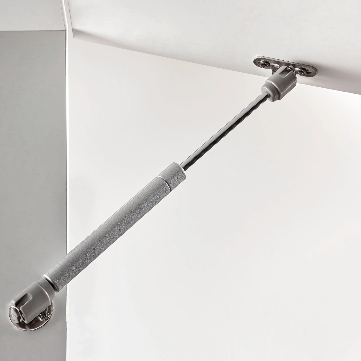 Hettich Klappenstütze Lift Basic aus Stahl und Kunststoff, montiert an einer weißen Möbelfront.