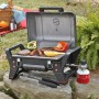 Evocamp Gasgrill mit Gaskartusche, Grillgut und Grillzange im Freien.
