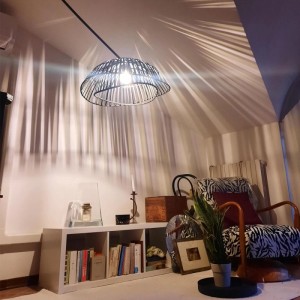 Orientalische Bogenlampe Pua mit schwarzem Bambusschirm in Wohnraum-Szene.