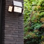 Schwarze Lutec LED-Solarleuchte Tuda mit 3 Leuchten an einer dunklen Backsteinwand.