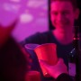 Hände stoßen mit roten und blauen Bierpong Bechern aus Kunststoff an. Party-Set für Trinkspiele.