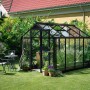 Juliana Gewächshaus Compact 6 in Anthrazit im Garten, mit Pflanzen und Gartengeräten.