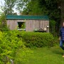 Mann mit Gardena Heckenschere 2in1 EnergyCut im Garten vor Holzhütte.